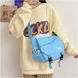 Lifestyle view of large light blue canvas messenger bag with double buckles and fashion tag