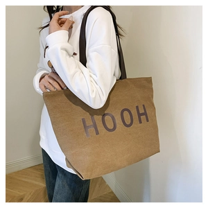 Détail d'un sac cabas en toile marron avec lettres HOOH violettes et fines bandoulières