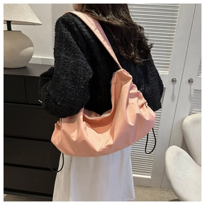 Détail du sac à bandoulière rose en nylon avec plis souples et fermeture à glissière