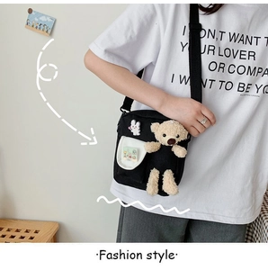 Détail du sac à bandoulière en toile noire avec ours en peluche 3D et broche de lapin