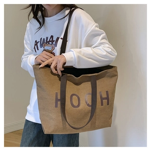 Vue latérale d'un grand sac cabas en toile marron avec inscription HOCH porté par un mannequin