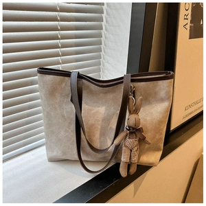 Close-up of beige tote bag with brown leather trim and a cute plush rabbit charm