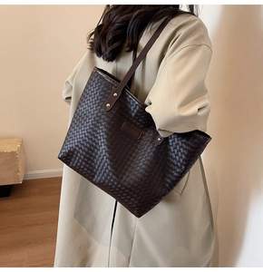 Detail of a dark brown woven leather tote bag with metallic studs and fashion logo