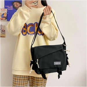 Detail of black canvas messenger bag featuring fashion patch and adjustable strap