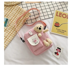 Détail du sac bandoulière en toile rose avec ours en peluche et broche lapin cartoon