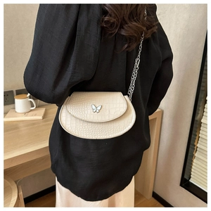 Close-up of beige crocodile pattern leather bag with silver butterfly buckle and chain