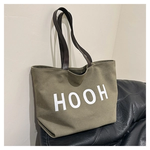 Détail du sac fourre-tout en toile vert olive avec anses brunes et logo HOOH blanc
