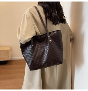 Detailed view of woven texture and gold rivets on dark brown leather tote bag