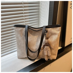 Detail of grey suede tote bag with brown leather handles and a cute bunny plush charm