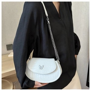 Detailed side view of white crocodile pattern saddle bag with butterfly buckle on model