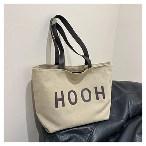 Détail du sac fourre-tout en toile beige avec imprimé HOOH et anses en cuir marron foncé