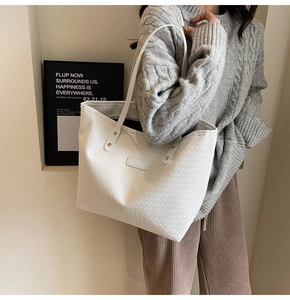Detail showing white woven tote bag with Fashion label carried by model in grey sweater