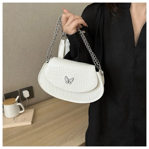 Close-up of white crocodile pattern saddle bag with a silver butterfly metal buckle