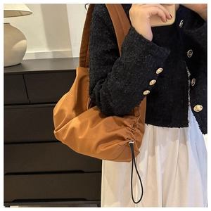 Gros plan d'un sac nuage en nylon marron caramel avec cordons sur l'épaule d'une femme