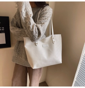 Close-up of white woven tote bag featuring fine cross-weave texture and fashion label