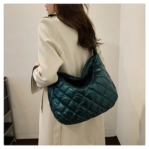 Deep emerald green quilted tote bag with metallic finish shown on model's shoulder