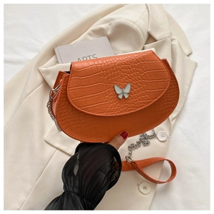 Detail of orange crocodile embossed saddle bag with silver butterfly clasp on a blazer