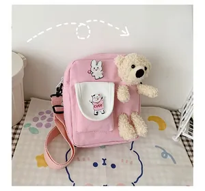 Vue détaillée du sac bandoulière rose en toile avec ours en peluche 3D et patchs