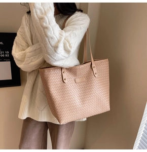 Detail of beige woven tote bag with FASHION leather tag and long shoulder straps