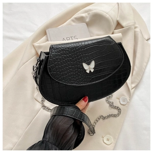 Close-up of black crocodile pattern leather mini saddle bag with white butterfly buckle