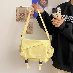 Detail view of the bright yellow canvas messenger bag featuring a secure flap with dual buckles