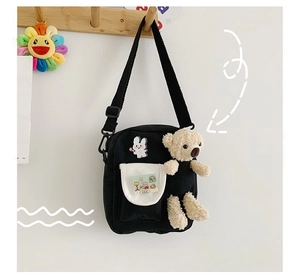 Détail du sac bandoulière en toile noire avec ours en peluche et crochet réglable