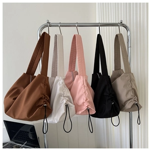 Cinq sacs à bandoulière en nylon assortis sur un présentoir moderne dans un cadre urbain