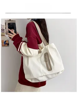 Close-up of white canvas tote bag featuring brown straps and vertical zipper pocket