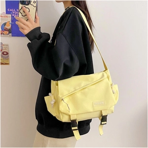 Detail of yellow canvas messenger bag featuring a flap cover and front zipper pocket