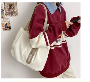 Detail view of large cream canvas tote bag with brown straps and zipper on model