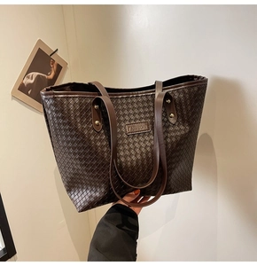 Close-up of deep brown woven texture tote bag with fashion embossed leather label
