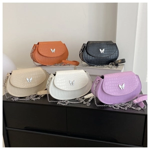 Detailed display of crocodile texture saddle bags with silver butterfly buckle and chain strap