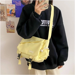 Detail of light yellow canvas messenger bag with fashion label and buckle closure