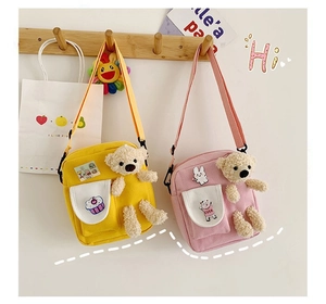 Détail de sacs à bandoulière en toile jaune et rose avec breloques ours en peluche
