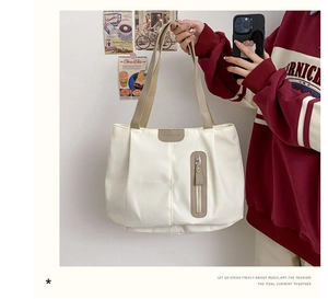 Close-up of cream canvas tote bag with brown contrast straps and fashion leather label