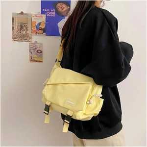 Detail of yellow canvas messenger bag with black buckle and Fashion label on shoulder