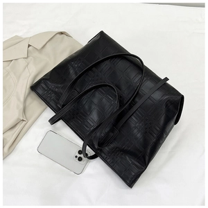 Detail of black leather tote bag with embossed grid pattern and thin shoulder straps