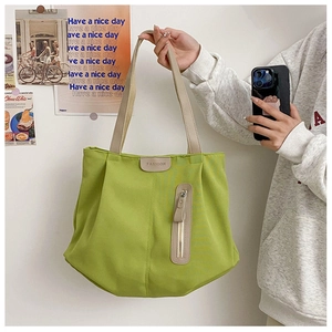 Detail of neon green canvas tote with brown leather fashion patch and zipper detail