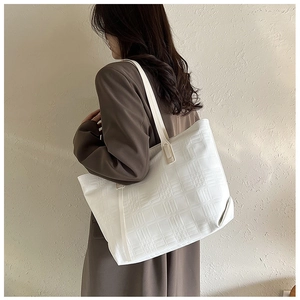 Detail view of a white tote bag with geometric grid embossing on high-quality faux leather