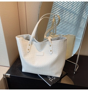 Detailed view of white woven tote bag texture with fashion label and gold rivet hardware
