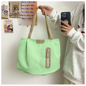 Detail of light green nylon tote bag with fashion leather label and vertical zipper pocket