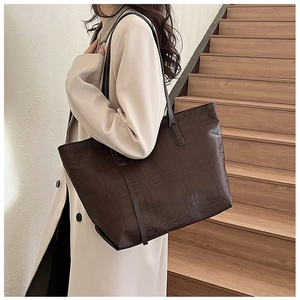 Detailed macro view of dark brown embossed checkered pattern on a large leather tote bag