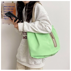 Close-up of mint green canvas tote bag featuring vertical zipper and brown leather puller