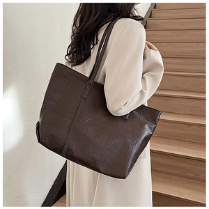 Detail of dark brown embossed checkered tote bag with shoulder strap in stylish setting