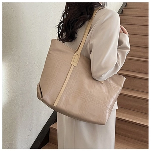 Close-up of geometric quilted texture and durable handle on the beige tote bag