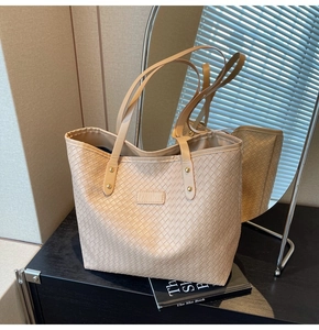 Detail view of beige woven texture tote bag with metallic studs and fashion label