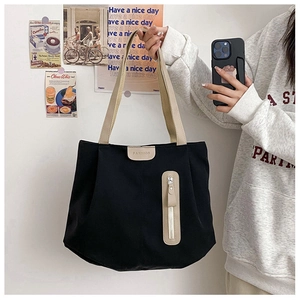 Detail of black canvas tote bag with beige handles and vertical zipper pocket design