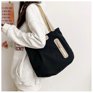 Detail of black canvas tote bag showing stitching and functional vertical zipper pocket