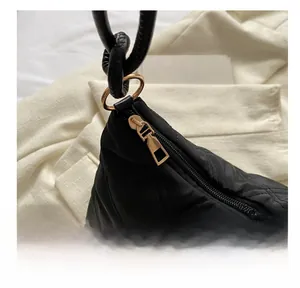 Close-up of the smooth golden metal zipper on a black quilted rhombic pattern handbag