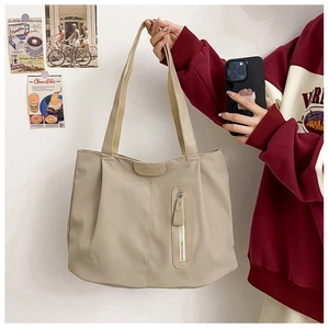Detail view of khaki canvas tote bag featuring front vertical zipper and leather clasp